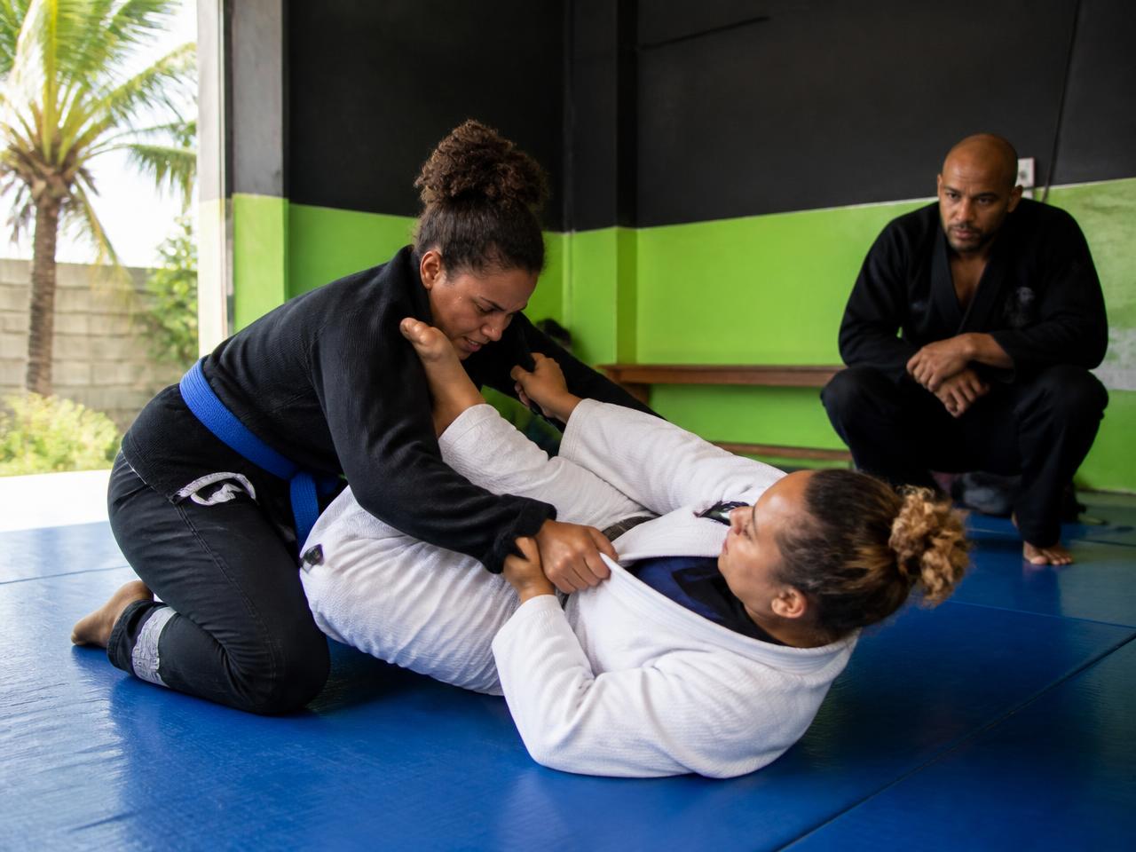 Two athletes rolling in gis on the mats